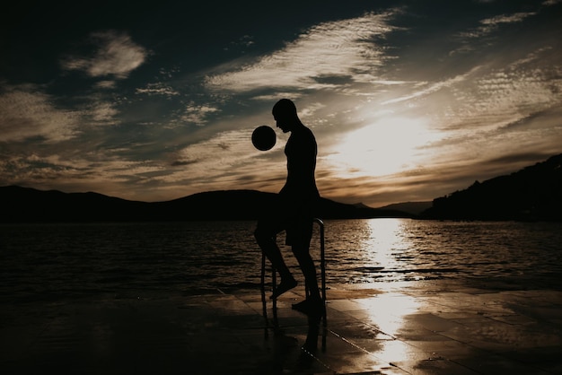 Silhouette d'homme jouant au football sur la plage