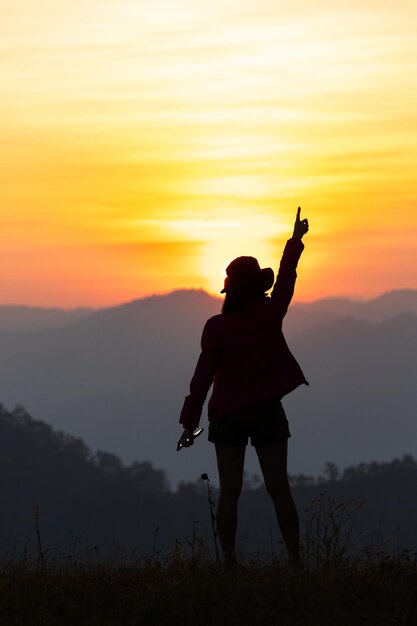 La silhouette de l'homme lève les mains sur le sommet du concept de montagne