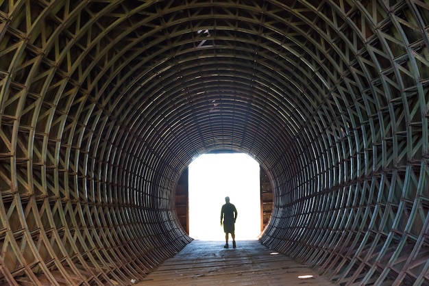 Silhouette d'un homme et lumière au bout du tunnel sombre