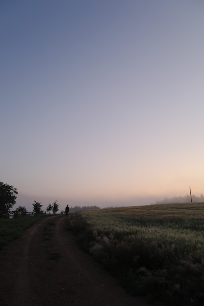 Silhouette d'un homme marchant dans un paysage de campagne pittoresque au lever du soleil