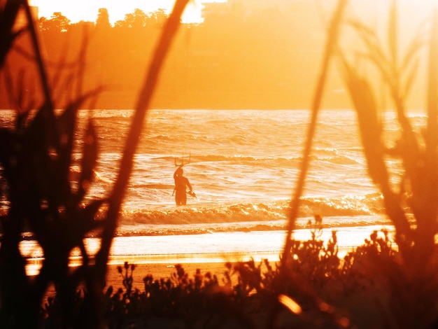 Photo silhouette d'homme en mer au coucher du soleil