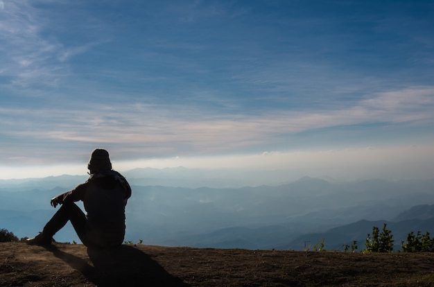 silhouette d&#39;un homme qui assis et regardant par-dessus le fond de paysage de montagnes