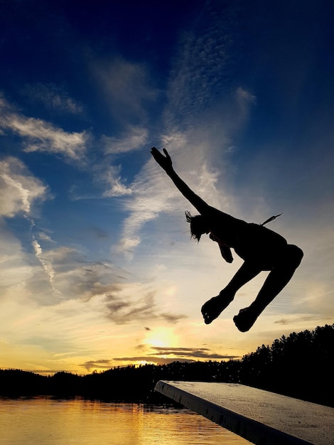 Photo silhouette d'un homme sautant contre le ciel au coucher du soleil