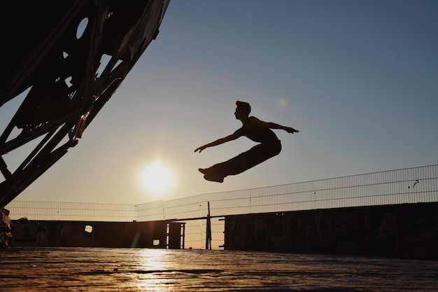 Photo silhouette d'un homme sautant contre le ciel au coucher du soleil