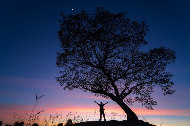 Silhouette un homme seul et un arbre pendant le coucher du soleil