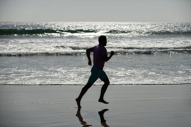 Silhouette d'homme sportif coureur sprint sur la réalisation en plein air de la plage