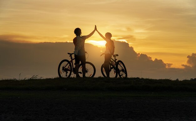 Silhouette d'un homme à vélo sur un champ contre le ciel au coucher du soleil