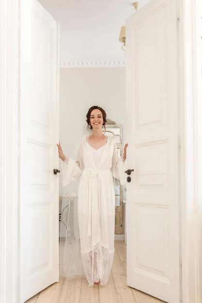 Silhouette de jeune belle fille mariée dans un peignoir se tient à la porte de la chambre et attend le marié