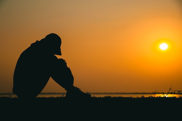 Silhouette d'une jeune femme debout regardant tristement le ciel au coucher du soleil