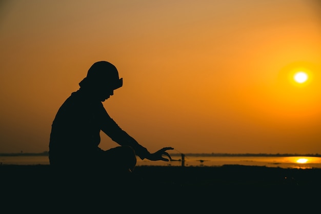 Silhouette d'une jeune femme debout regardant tristement le ciel au coucher du soleil