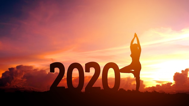 Silhouette jeune femme pratiquant le yoga sur 2020 nouvel an