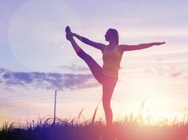 Silhouette jeune femme pratiquant le yoga à l'arrière-cour