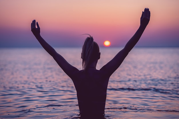 Photo silhouette de jeune femme pratiquant le yoga sur la plage au lever du soleil