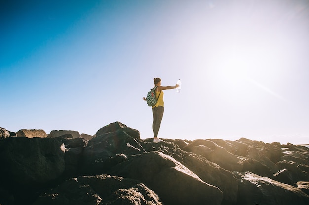 Silhouette d&#39;une jeune femme pratiquant le yoga sur une rive rocheuse