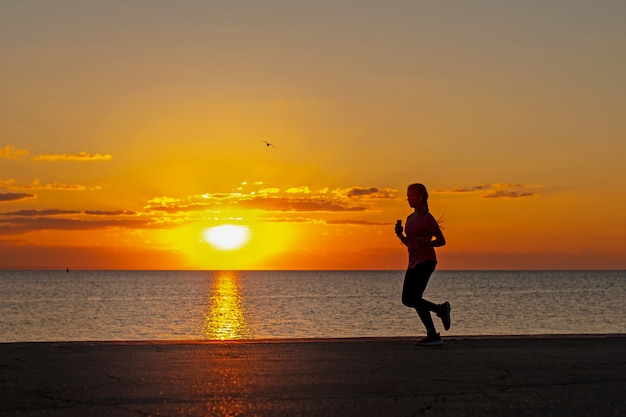 silhouette de jeune fille en cours d'exécution au lever du soleil