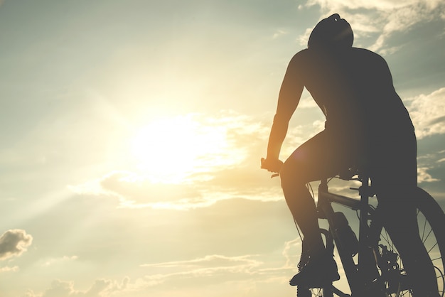 Silhouette jeune homme du cyclisme sur fond de coucher de soleil