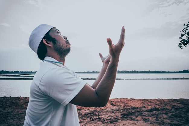 Silhouette Jeune homme musulman asiatique priant au coucher du soleil Concept du festival Ramadan