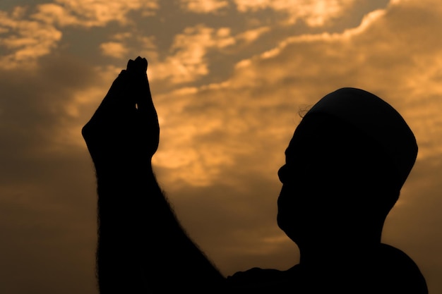 Silhouette Jeune homme musulman asiatique priant au coucher du soleil Concept du festival Ramadan