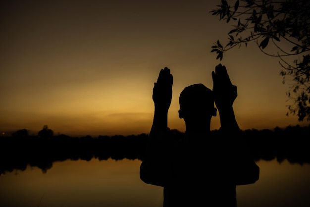 Silhouette Jeune homme musulman asiatique priant au coucher du soleil Concept du festival Ramadan