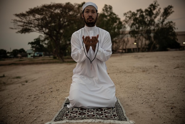 Silhouette Jeune homme musulman asiatique priant au coucher du soleil Concept du festival Ramadan