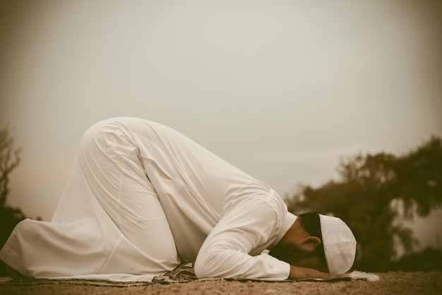 Silhouette Jeune homme musulman asiatique priant au coucher du soleil Concept du festival Ramadan