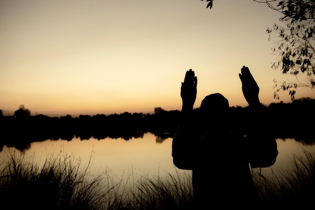 Silhouette Jeune homme musulman asiatique priant au coucher du soleil Concept du festival Ramadan