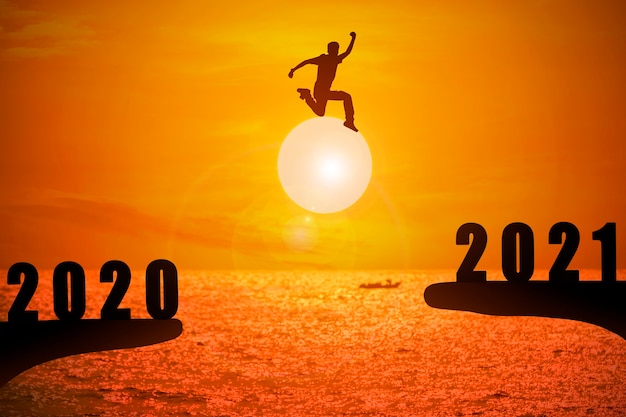 Photo silhouette de jeune homme sautant entre 2020 et 2021 ans avec beau coucher de soleil sur la mer.