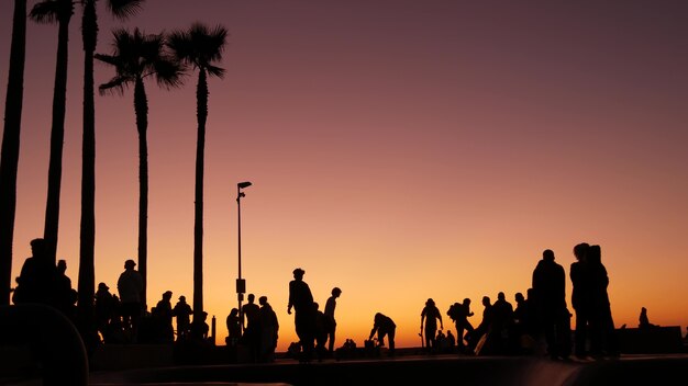 Silhouette de jeune skateur sautant équitation longboard, coucher de soleil d'été