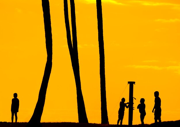 Photo silhouette de jeunes enfants sur la douche de plage