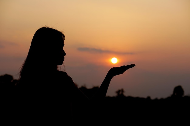 Silhouette de main humaine levée pour faire un vœu fond de coucher de soleil