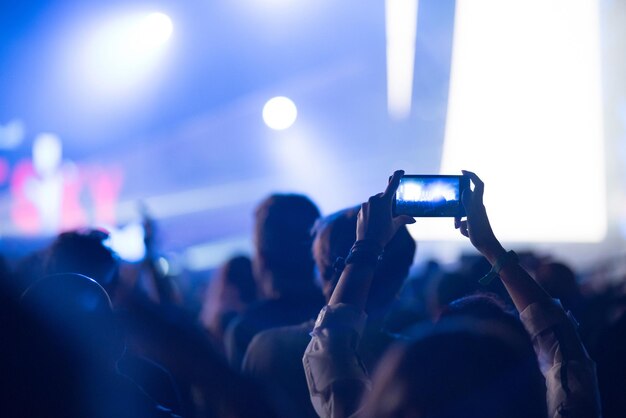 Silhouette de mains levées tenant un concert de musique d'enregistrement de téléphone intelligent