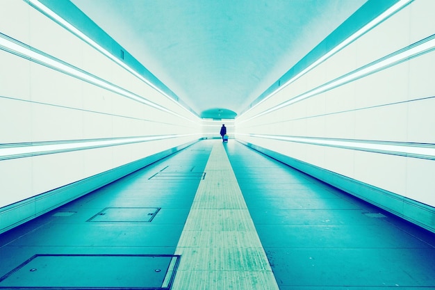 Photo silhouette marchant dans un tunnel éclairé en bleu