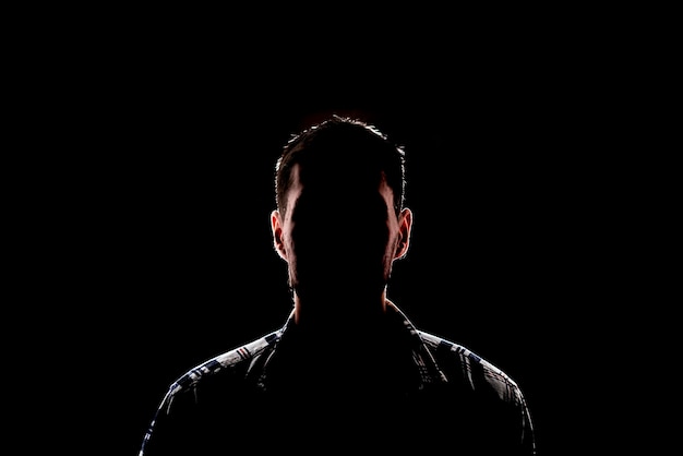 Une silhouette masculine sombre isolée dans le portrait de studio d'ombre