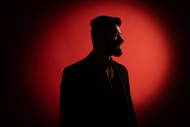 Silhouette masculine sombre. Silhouette d'homme à barbe sur fond rouge avec espace de copie