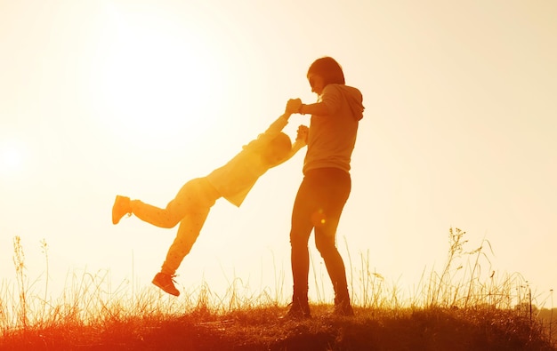 Silhouette de mère et petite fille au coucher du soleil