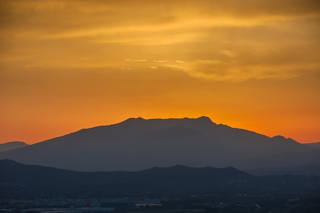 Une silhouette d'une montagne contre un ciel coucher de soleil.