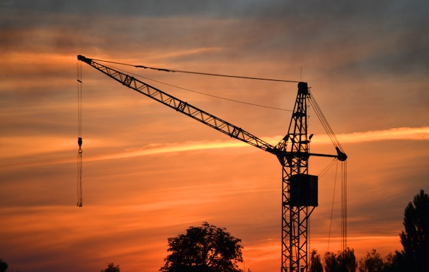 Silhouette noire d'une grue de construction au crépuscule, à l'aube