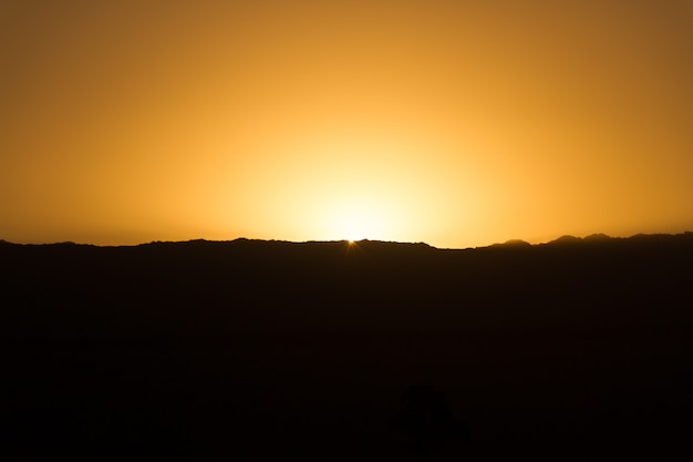 Silhouette noire des montagnes au coucher du soleil avec un ciel doré