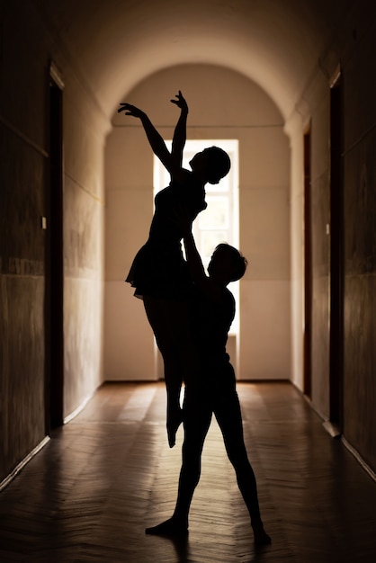 Silhouette de paire de danseurs professionnels dans le couloir de l'ancien théâtre effectuant des gimmicks de ballet