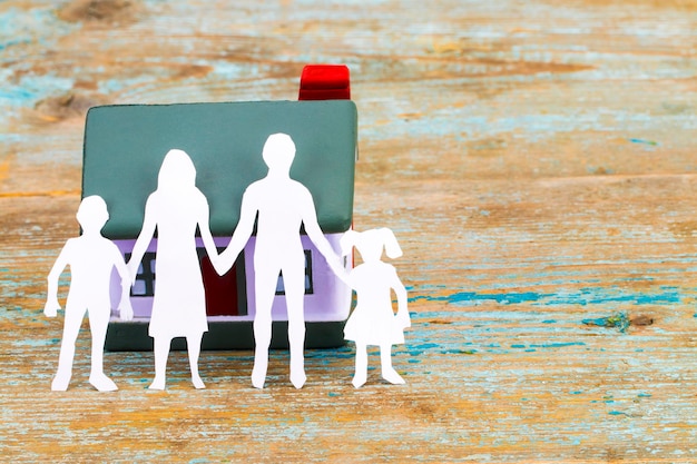 Photo silhouette en papier de la famille et de la maison sur un bureau en bois. notion d'assurance.