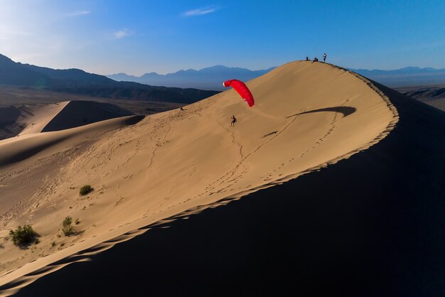 Silhouette de parapente volant dans la dune