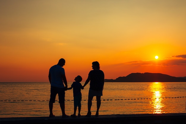 Silhouette de parents avec un enfant en famille sur la plage