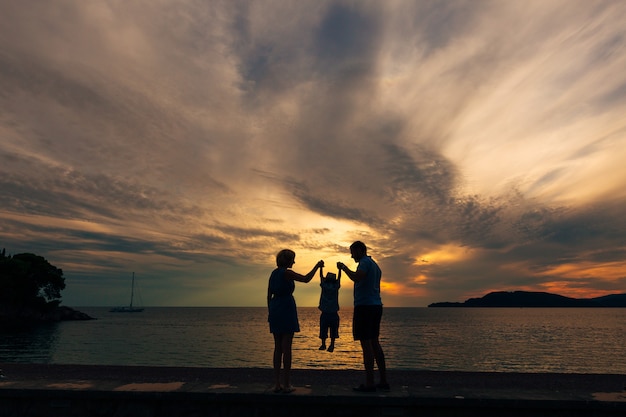 Silhouette de parents avec un enfant en mer famille sur la plage j'ai