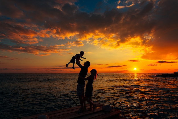 Silhouette de parents avec un enfant en mer famille sur la plage je