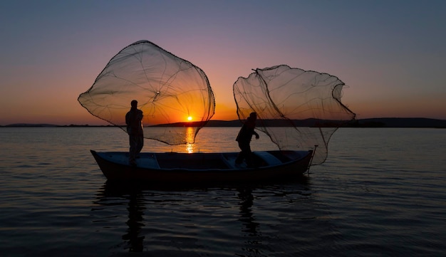 Silhouette de pêcheurs avec un soleil jaune et orange en arrière-plan