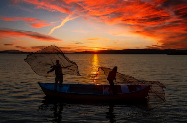 Silhouette de pêcheurs avec un soleil jaune et orange en arrière-plan