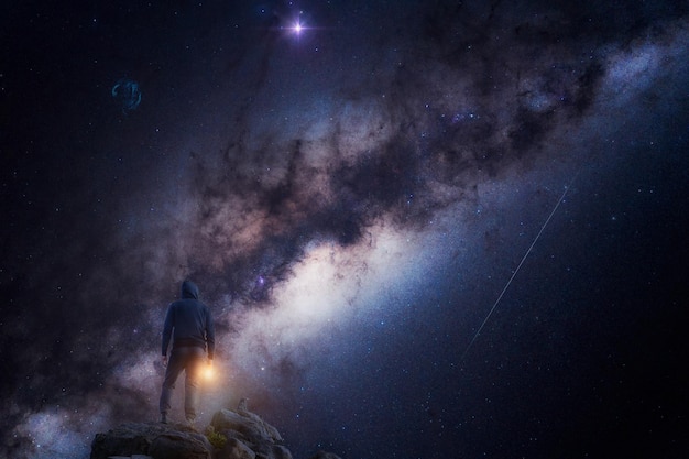 Silhouette d'une personne de dos la nuit avec la voie lactée et le cosmos en arrière-plan