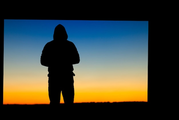 Silhouette d'une personne sur le fond d'un ciel jaune-bleu