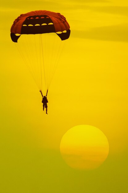 Photo silhouette d'une personne en parapente contre un ciel jaune
