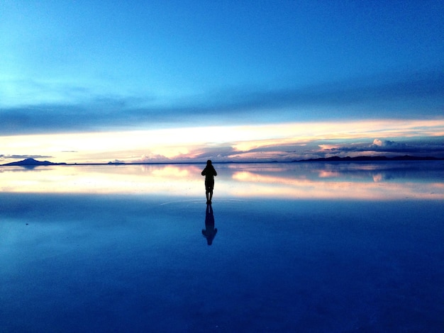 Photo silhouette d'une personne sur la plage contre le ciel au coucher du soleil
